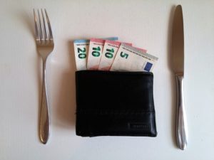 Eura v peněžence na stole a příbor